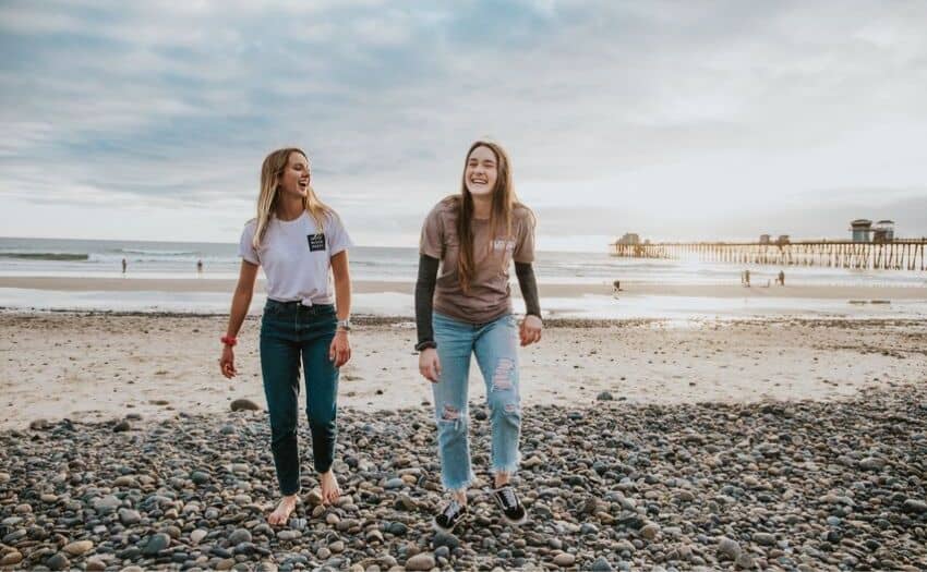 two women walking on the beach smiling