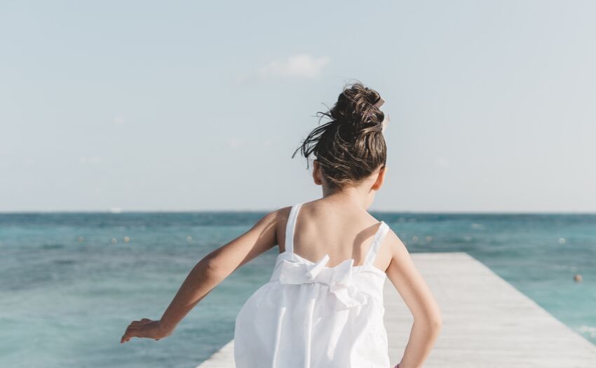 little girl in white dress running on a dock