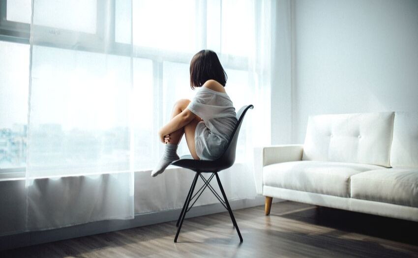 Girl sitting alone on a chair in a living room