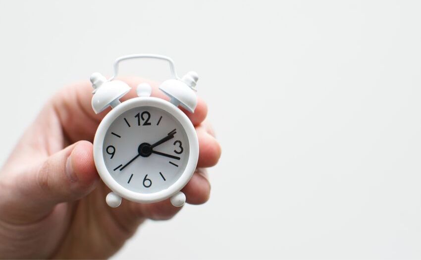 person holding a small clock in hand