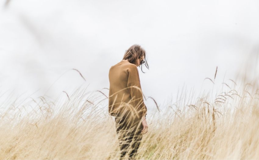 How to get over regret - sad woman standing in grass field