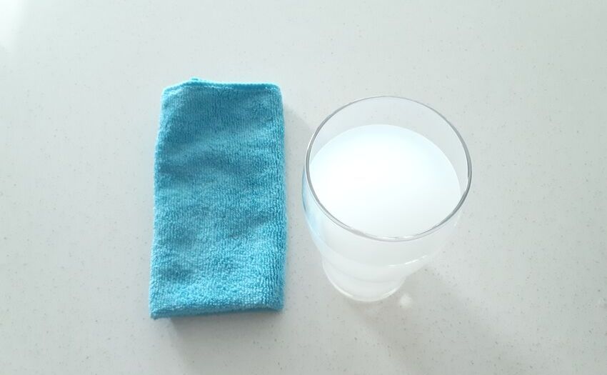 glass of milky rice water next to a blue microfiber towel