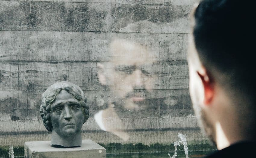 man looking at a sad statue