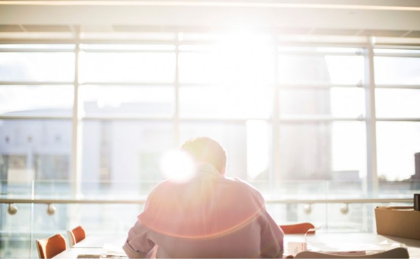 man sitting at a table with sunlight streaming in the window