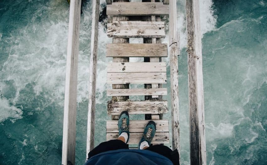 image of a person's feet walking across a broken bridge