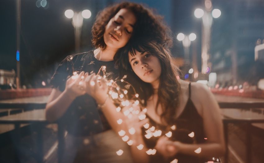 two women holding string lights