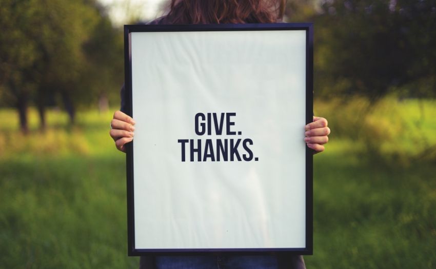 person holding a sign that says "give thanks"