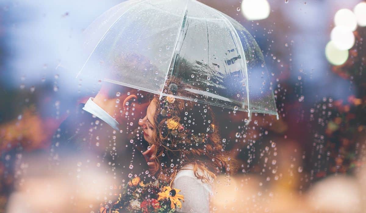 rainy day date ideas feature image woman and man hugging under an umbrella