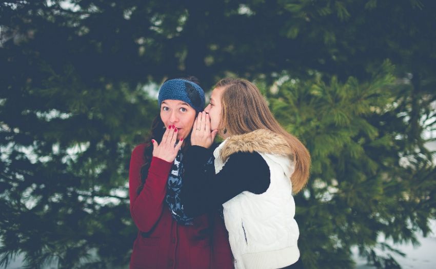 a girl whispering in another girl's ear