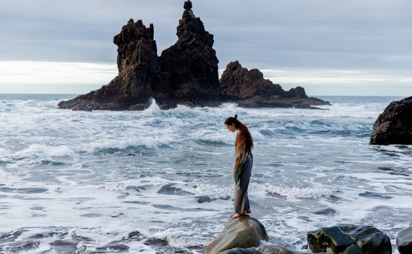 woman standing on a rock in the ocean 