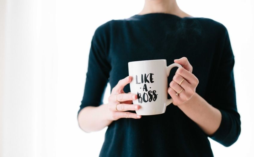 woman in a black dress holding a cup that says "like a boss"