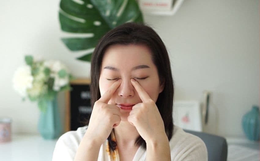 Sabrina demonstrating where to find the Jingming facial acupressure point